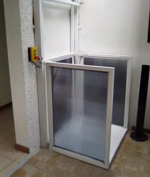 Plataforma elevadora con cerramiento de policarbonato y botonera de llamada en interior de vivienda